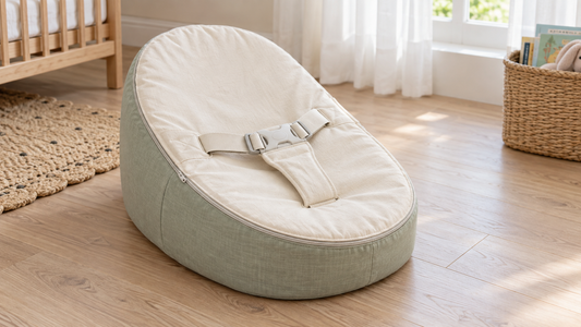 Illustrative nursery scene with an empty baby bean bag, a removable cream liner and a three-point harness.